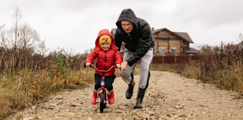 Father helping boy ride a bicycle.