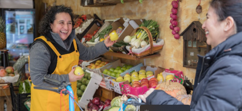 Fruit and vegetable shop owner smiling at a customer